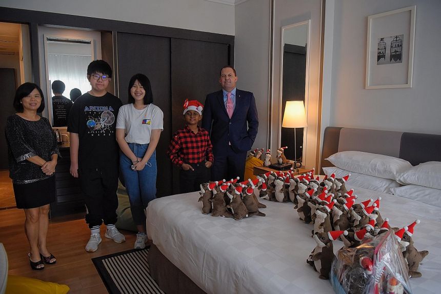 STSPMF general manager Tan Bee Heong and Millennium Hotels and Resorts vice-president of operations (SEA) Lee Richards with beneficiaries Loh Miao Xin (centre), 18; her brother Khim San, 13; and S. Mugunthesh, nine, at Orchard Hotel yesterday, where the youngsters received otter plushies and Christmas gift hampers.  ST PHOTO: MARK CHEONG