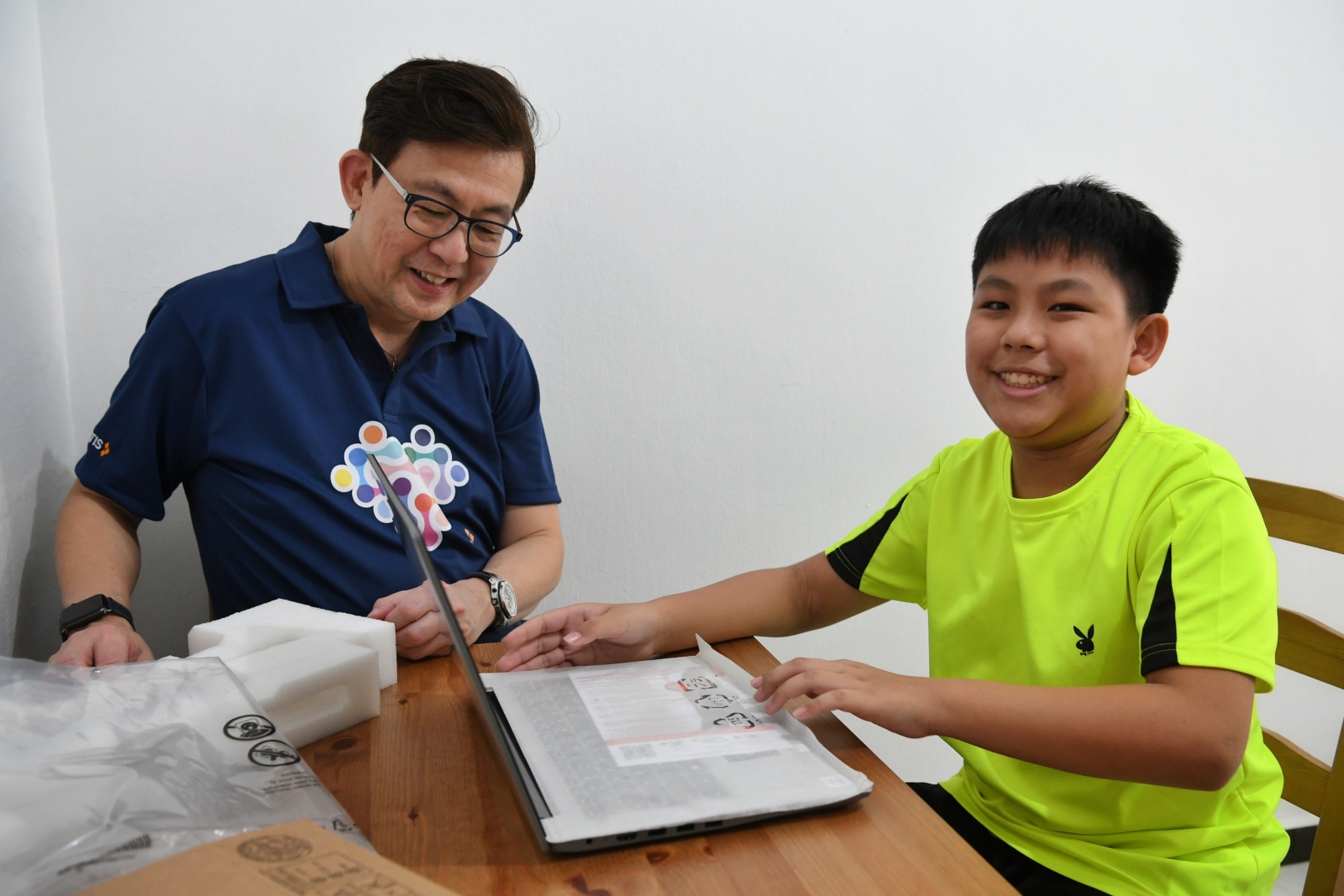 Primary 5 pupil Jaron Lim opening a new laptop gifted from Certis president and group CEO Paul Chong. ST PHOTO: CHONG JUN LIANG